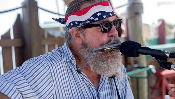 бородатый музыкант играет на гармонике